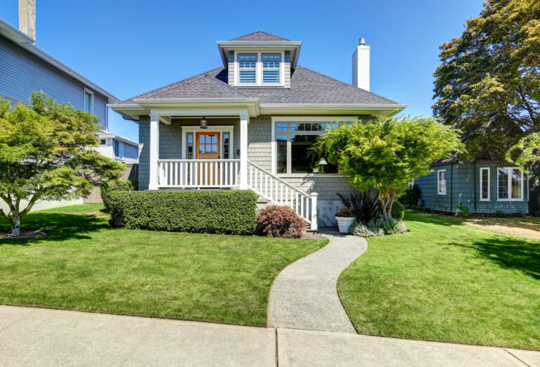Single-family American craftsman house exterior. Blue sky background and nicely trimmed front yard.
