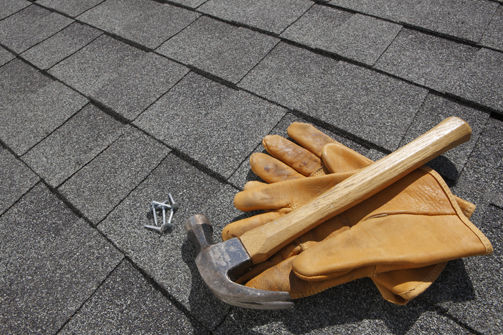Hammer and pair of gloves and nails on rooftop